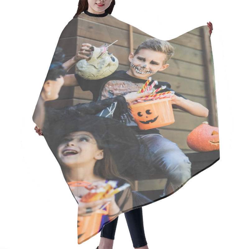 Personality  Smiling Boy In Skeleton Halloween Costume Holding Skull And Bucket Of Sweets Near Blurred Mom And Sisters Hair Cutting Cape