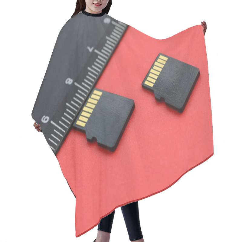 Personality  Two Small Micro SD Memory Cards Lie On A Red Background Next To A Black Ruler. A Small And Compact Data And Information Store Hair Cutting Cape