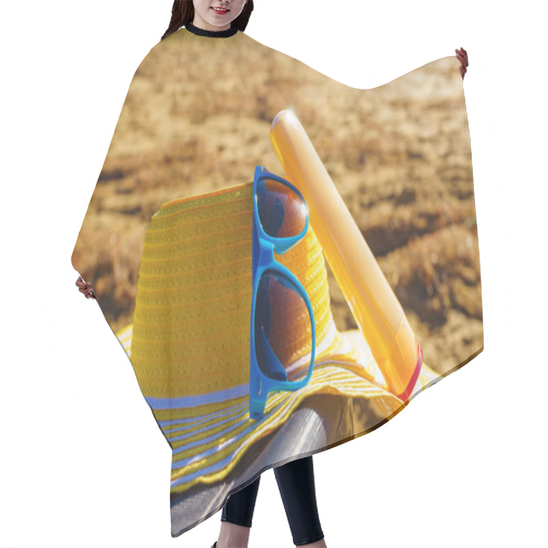 Personality  Sun Protection Accessories On Sea Shore. Blue Sunglasses, Yellow Straw Hat And Sunscreen Lotion On Sandy Beach. Summer And Holidays. Hair Cutting Cape