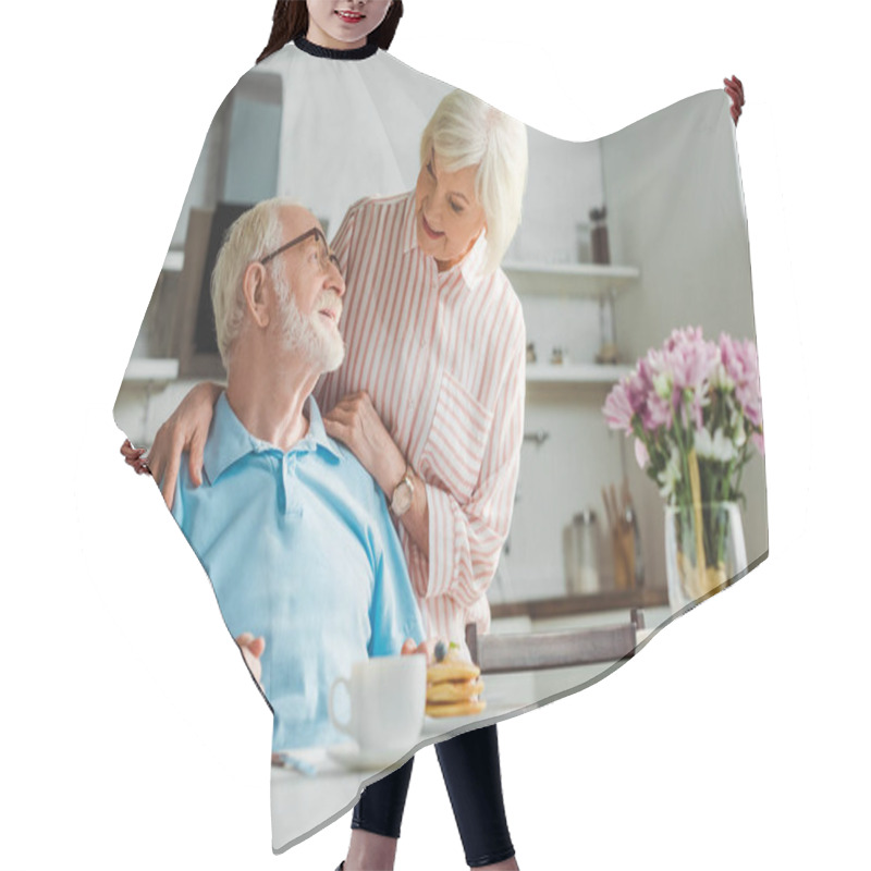 Personality  Selective Focus Of Senior Woman Hugging Smiling Husband By Coffee And Pancakes On Table Hair Cutting Cape