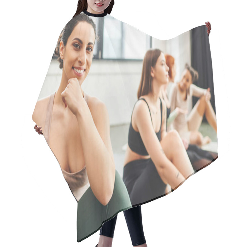 Personality  Cheerful Multiracial Woman In Sportswear Looking At Camera Near Multiethnic Female Friends Sitting On Blurred Background During Yoga Class, Wellness And Mental Health Concept Hair Cutting Cape