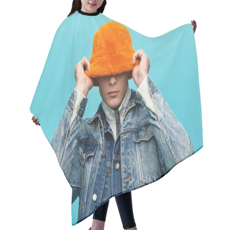 Personality  A Young Man With A Fluffy Orange Hat Smiles In Front Of A Bright Blue Wall. Hair Cutting Cape