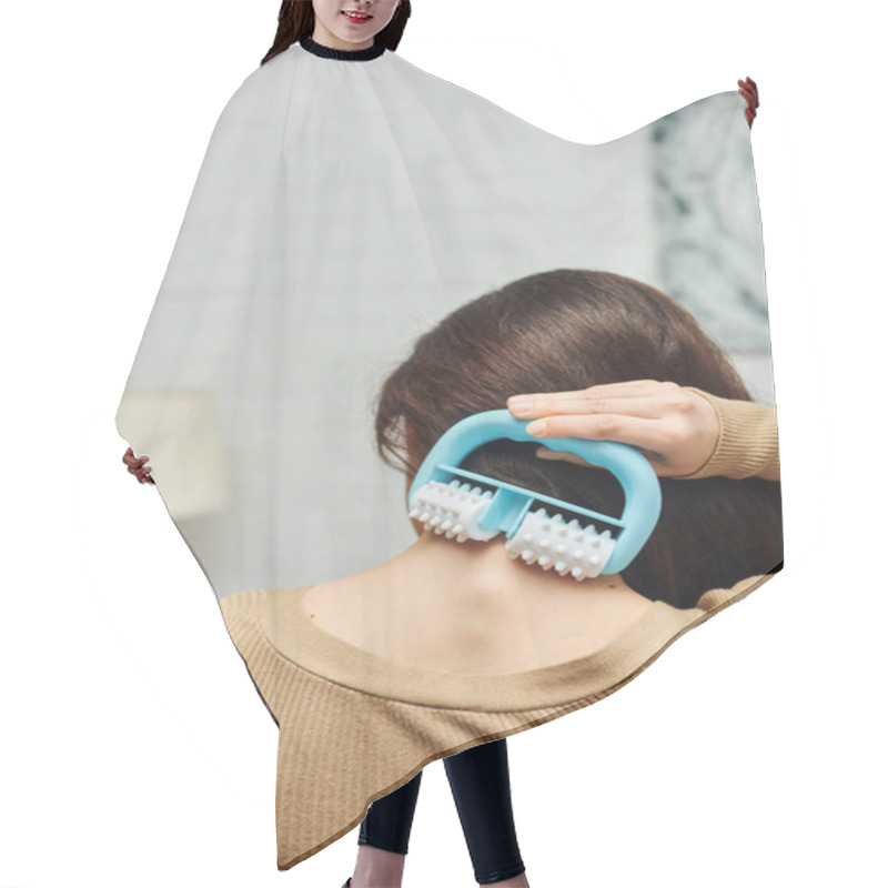 Personality  Back View Of Young Woman In Casual Brown Jumper Holding Handled Massager And Doing Self-massage Of Back In Blurred Living Room, Lymphatic System Support And Home-based Massage, Tension Relief Hair Cutting Cape