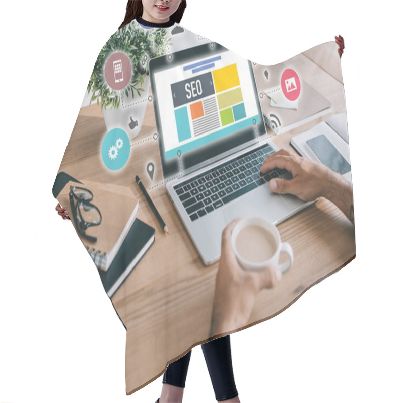 Personality  Cropped View Of Developer Using Laptop With SEO Icons And Holding Cup Of Coffee Hair Cutting Cape