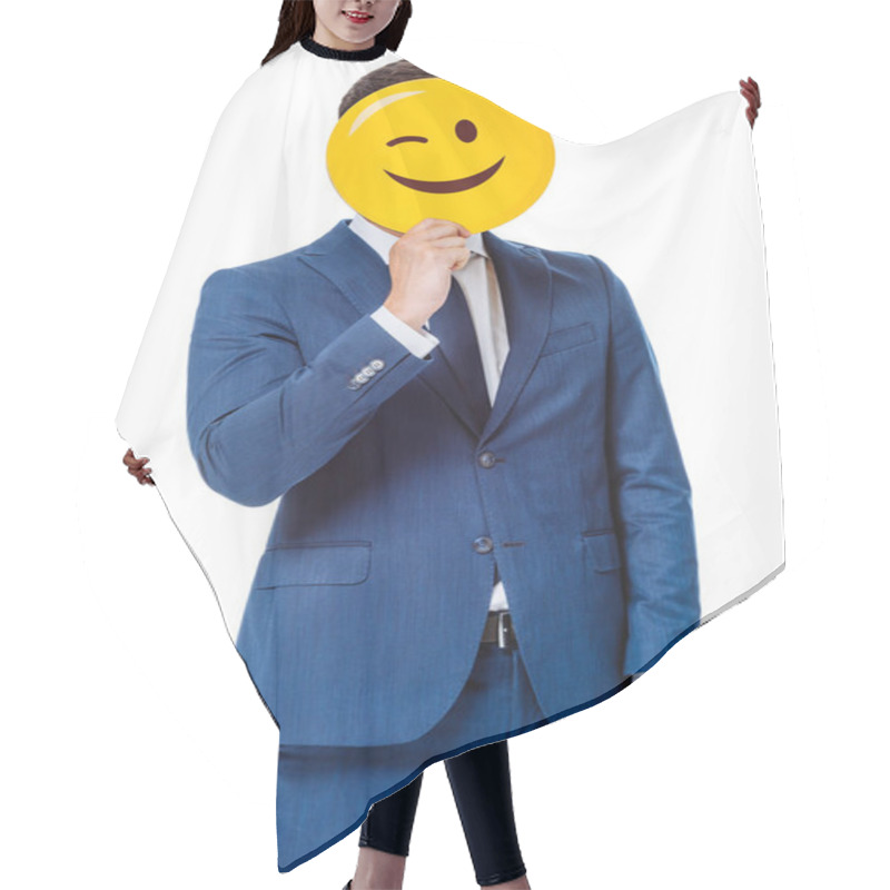 Personality  KYIV, UKRAINE - AUGUST 12, 2019: Businessman In Blue Suit Holding Winking Smiley In Front Of Face Isolated On White Hair Cutting Cape