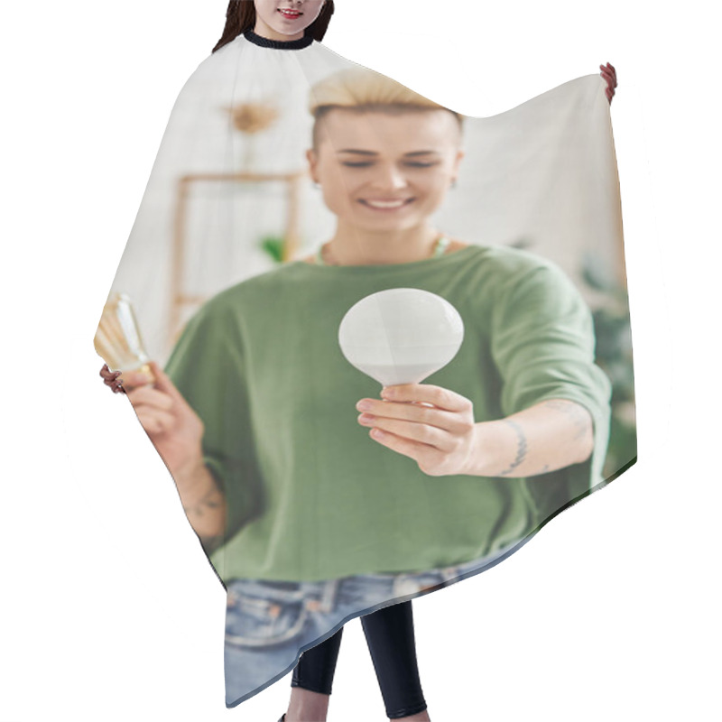 Personality  Young And Tattooed Woman In Casual Clothes Holding Energy Saving Light Bulbs And Smiling In Living Room On Blurred Background,  Sustainable Lifestyle And Environmentally Conscious Concept Hair Cutting Cape