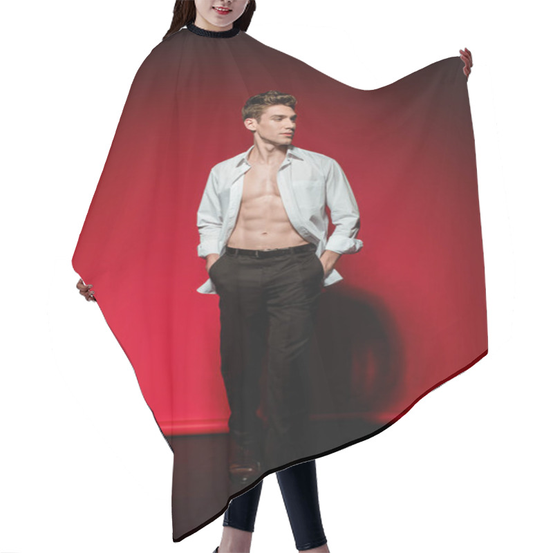 Personality  Sexy Young Elegant Man In Unbuttoned Shirt With Muscular Bare Torso And Hands In Pockets On Red Background Hair Cutting Cape