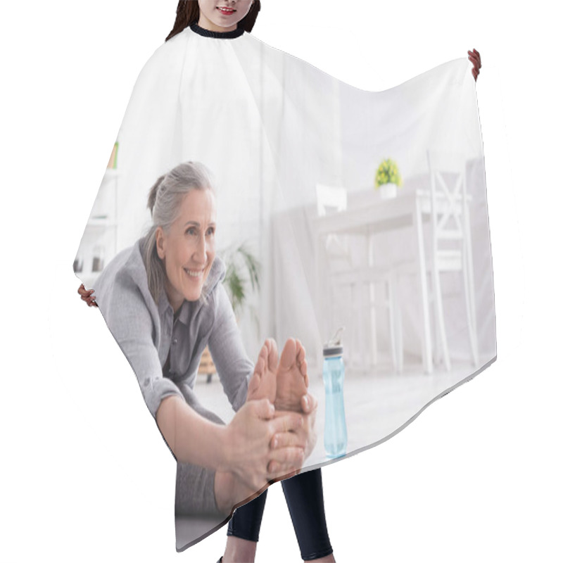 Personality  Cheerful Mature Woman With Grey Hair Stretching On Yoga Mat Near Sports Bottle  Hair Cutting Cape