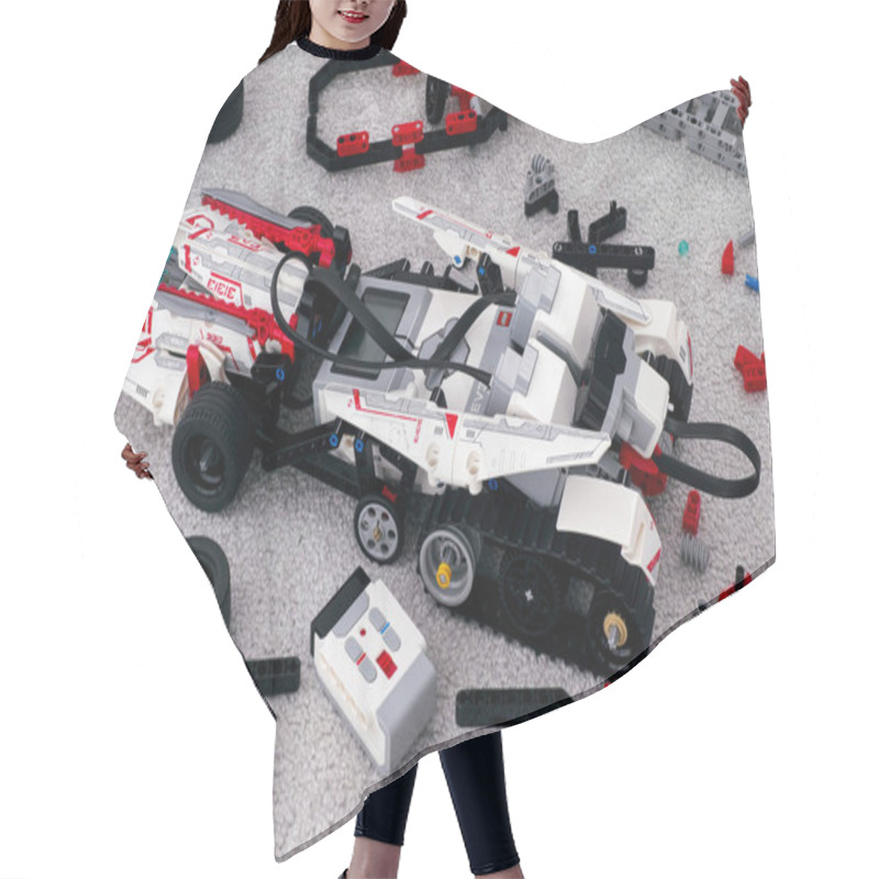 Personality  LEGO MINDSTORMS EV3 robot on room floor with some bricks and blo hair cutting cape