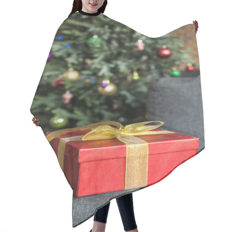 Personality  Close-up View Of Red Gift Box With Golden Bow On Couch And Decorated Christmas Tree Behind  Hair Cutting Cape