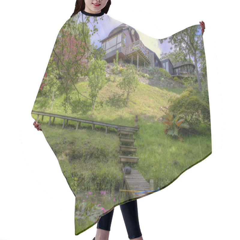 Personality  A Low Down Perspective Of A Green Downhill Meadow On A Bright Sunny Day, There Is A Small Stream Of Water Flowing At The Bottom Of The Meadow And A Wooden Walkway Leading From The Modern House Down Over The Stream Of Water.  Hair Cutting Cape