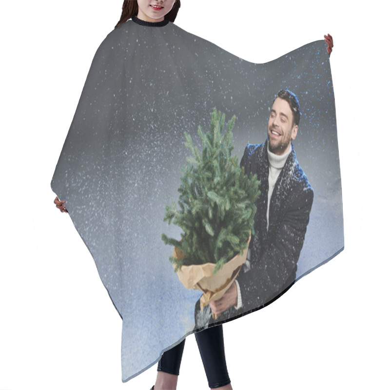 Personality  A Cheerful Young Man Sits In Snow, Happily Cradling A Small Christmas Tree Surrounded By Snowflakes. Hair Cutting Cape