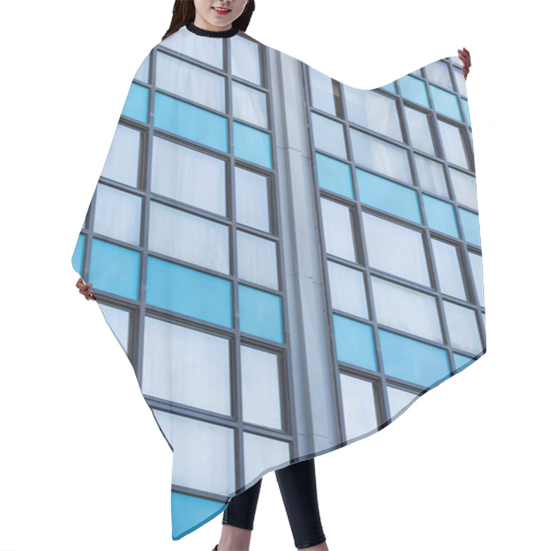 Personality  A Modern Glass Building Facade With A Grid Pattern. The Blue-tinted Windows, Some Adorned With Light Curtains, Create A Blend Of Transparency And Reflection. Geometric Repetition, Urban Architectural Hair Cutting Cape