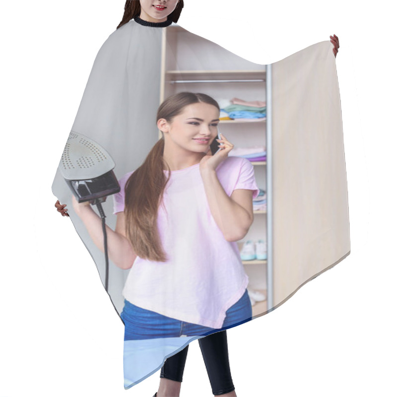 Personality  Attractive Young Woman With Iron Talking By Phone At Home Hair Cutting Cape