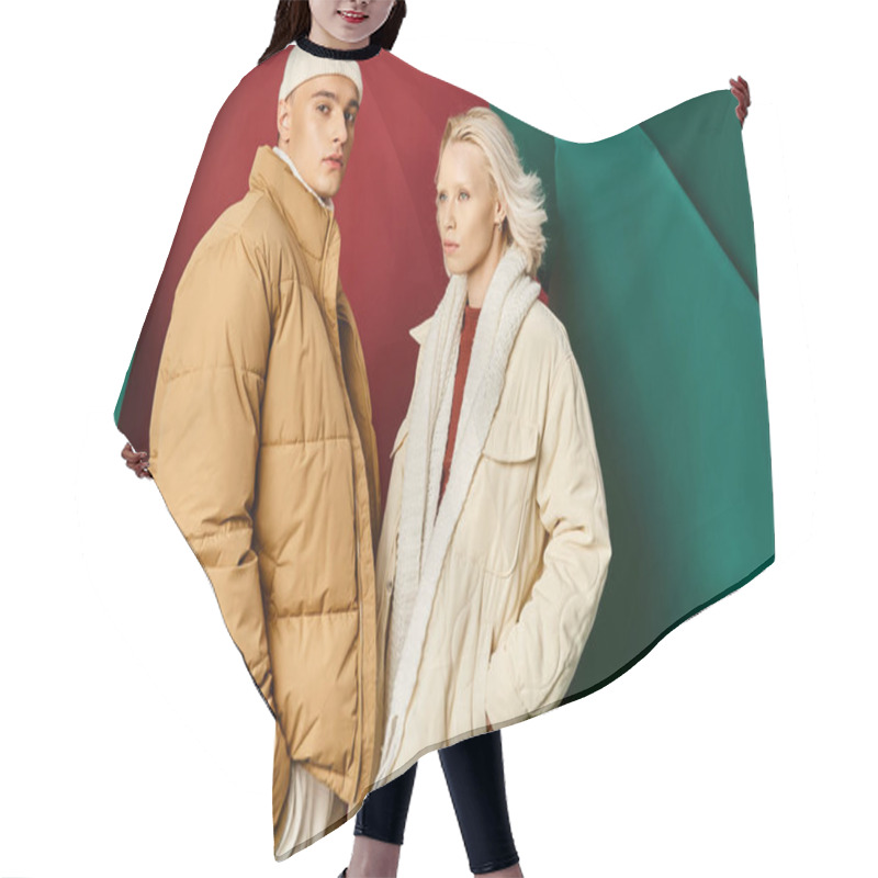 Personality  Couple In Trendy Winter Jackets Posing With Hands In Pockets On Red With Turquoise Backdrop Hair Cutting Cape