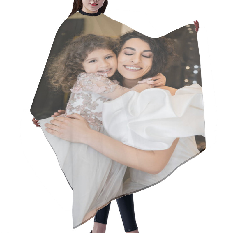 Personality  Cheerful Little Girl In Floral Attire Hugging Tight Her Charming Middle Eastern Mother With Closed Eyes In White Wedding Dress With Puff Sleeves And Ruffles While Smiling In Bridal Boutique  Hair Cutting Cape