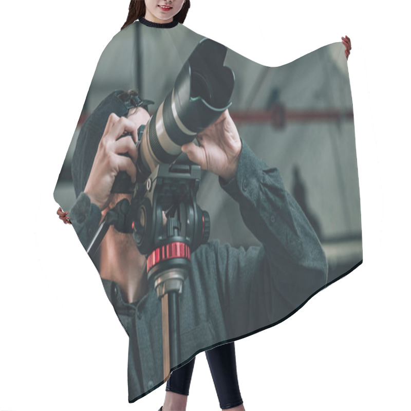 Personality  Low Angle View Of Videographer With Camera On Tripod In Photo Studio Hair Cutting Cape