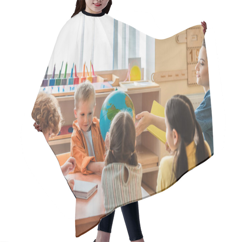 Personality  Teacher Pointing At Globe While Talking To Kids During Lesson In Montessori School Hair Cutting Cape