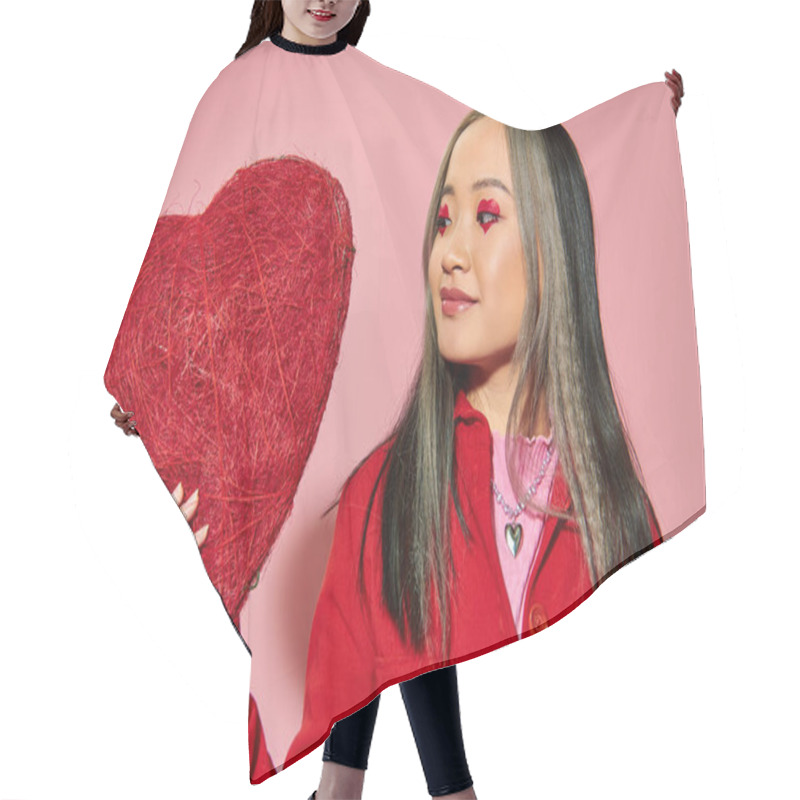 Personality  Valentines Day, Joyful Asian Woman With Vibrant Eye Makeup Holding Red Heart On Pink Backdrop Hair Cutting Cape