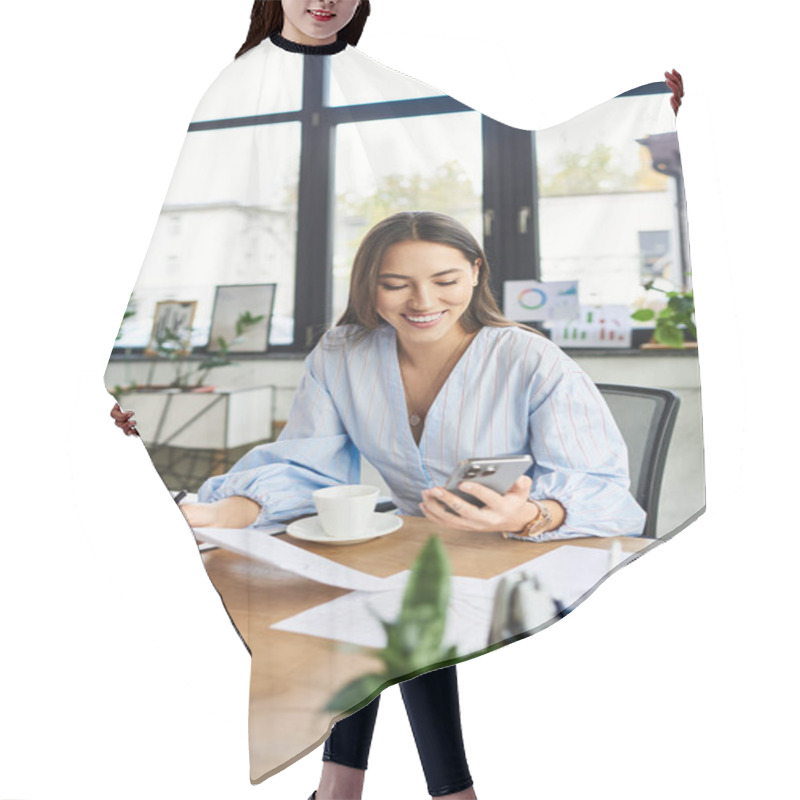 Personality  Young Woman Smiles While Using Her Phone In A Well Lit Office Filled With Plants. Hair Cutting Cape