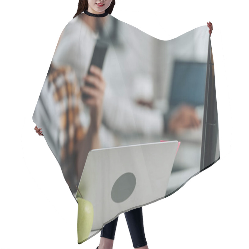 Personality  Selective Focus Of Young Programmer Holding Smartphone While Sitting Near Laptop In Office Hair Cutting Cape