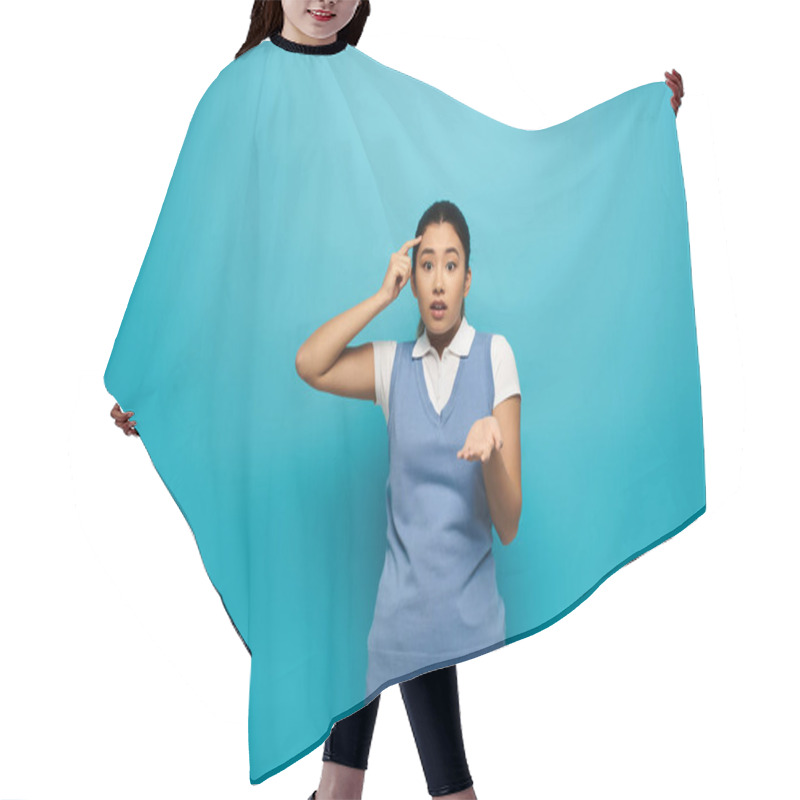 Personality  Lost Asian Woman In Smart Attire, Hand On Head, Confused, Hand Outstretched, On Bright Blue Backdrop. Hair Cutting Cape