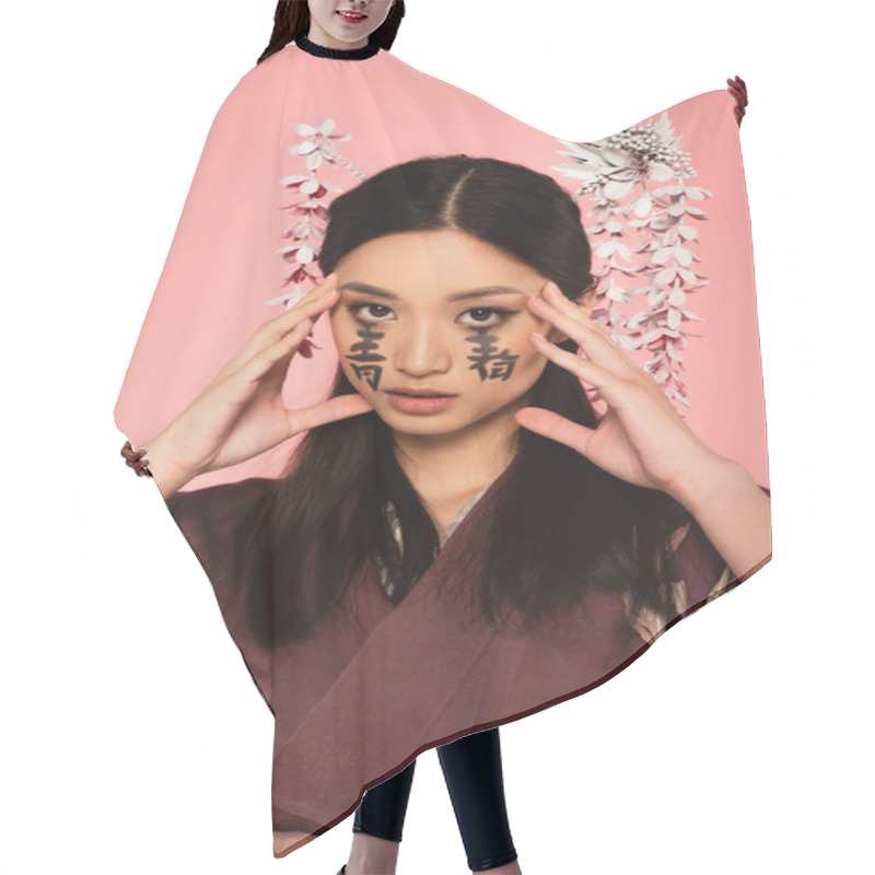 Personality  Asian Woman With Hieroglyphs On Face Looking At Camera Isolated On Pink  Hair Cutting Cape