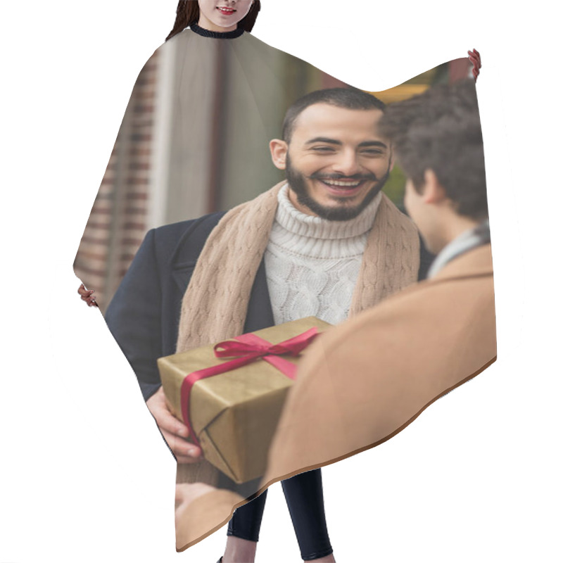 Personality  Cheerful Bearded Gay Man Holding Christmas Present Near Blurred Boyfriend On Street Hair Cutting Cape