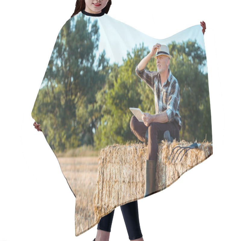 Personality  Senior Farmer Using Digital Tablet While Sitting On Bale Of Hay  Hair Cutting Cape