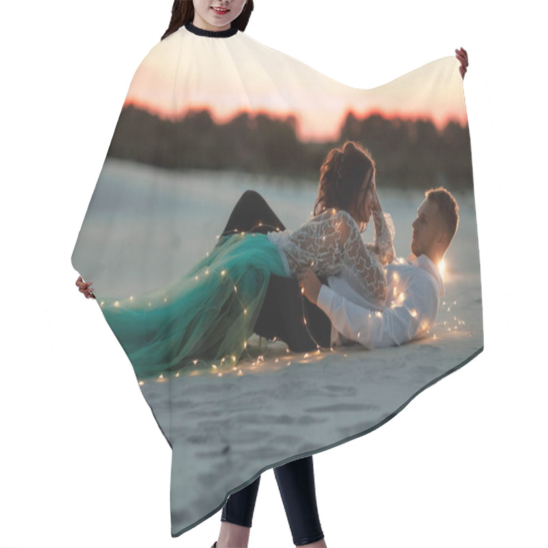 Personality  Bride And Groom Lie In Desert Next To Garland Of Light Bulbs At Sunset. Hair Cutting Cape