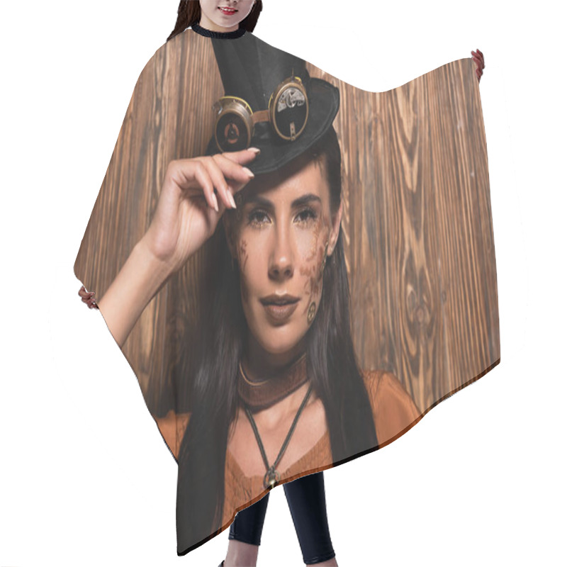 Personality  Front View Of Steampunk Woman Touching Top Hat With Goggles Looking At Camera On Wooden Hair Cutting Cape