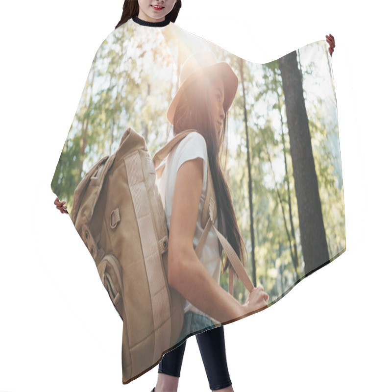 Personality  Young Traveler Woman Wearing Backpack And Hat In Hand Among Trees At Sunset. Hipster Girl With Traveling Backpack In Forest. Lens Flare Effect Hair Cutting Cape