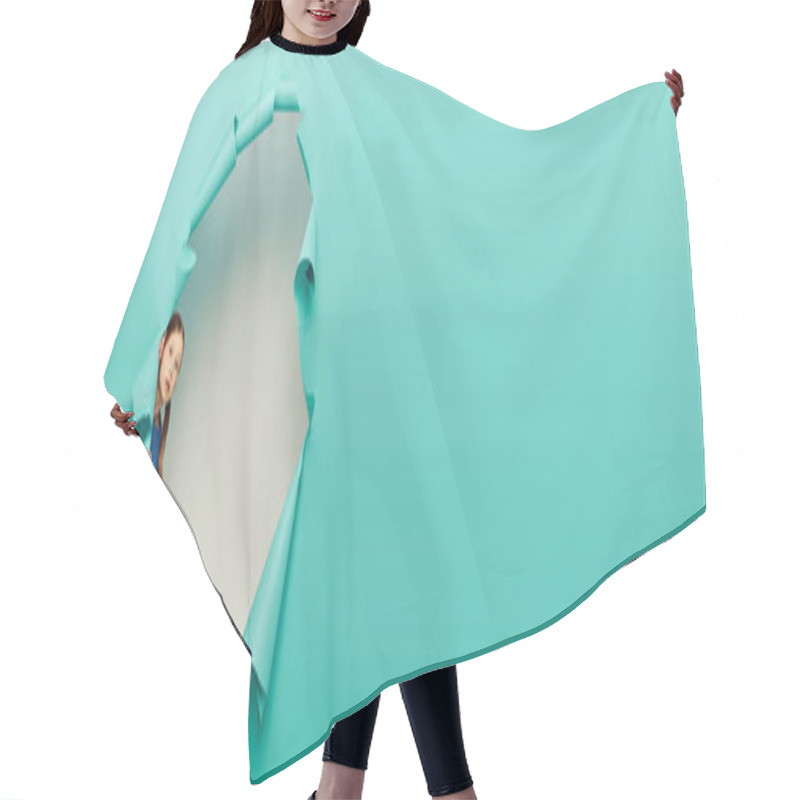 Personality  Feared Preteen Red Haired Girl Looking At Camera While Standing Behind Hole In Blue Paper And Celebrating Child Protection Day On White Background, Banner  Hair Cutting Cape