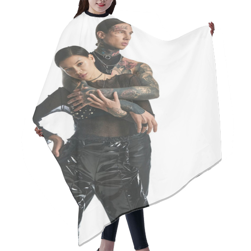 Personality  A Young, Stylish, Tattooed Couple Dressed In Latex Clothing Poses In A Studio Against A Grey Background. Hair Cutting Cape