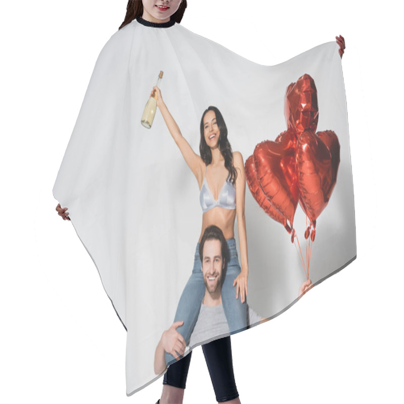 Personality  Man With Heart-shaped Balloons Piggybacking Sexy And Happy Woman With Champagne Bottle On Grey Hair Cutting Cape