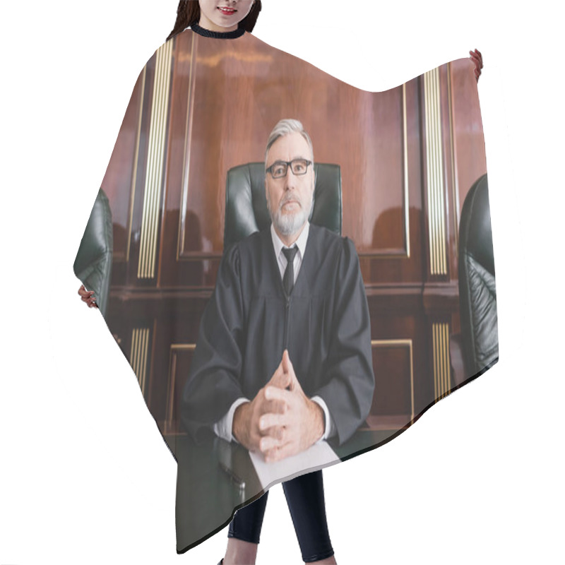 Personality  Senior Judge In Mantle And Eyeglasses Sitting With Clenched Hands Near Gavel And Paper On Desk Hair Cutting Cape