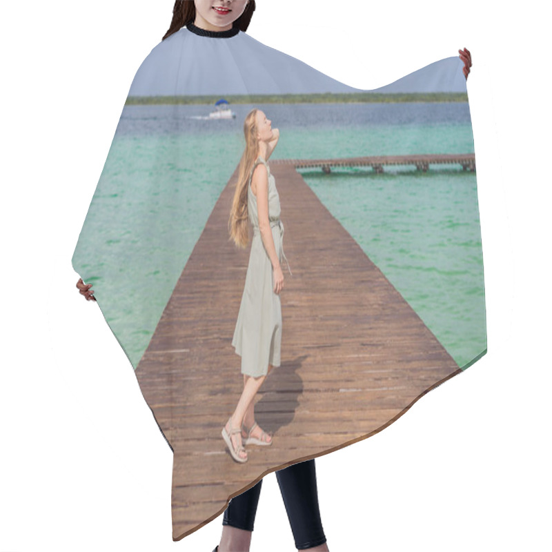 Personality  Female Tourist In A Turquoise Dress Standing On A Wooden Pier Over The Turquoise Waters Of Bacalar Lake, Mexico. Peaceful Tropical Travel Destination Concept. Hair Cutting Cape