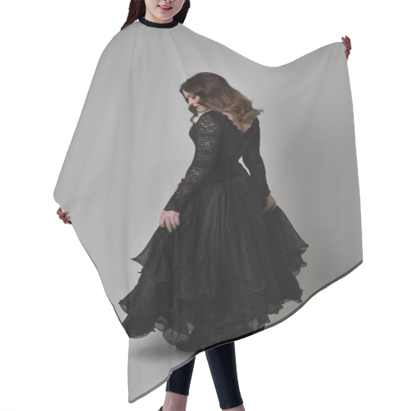 Personality  Full Length Portrait Of Brunette Girl Wearing Long Black Lace Gown Wit Corset. Standing Pose With Back To The Camera. Isolated On Grey Studio Background. Hair Cutting Cape