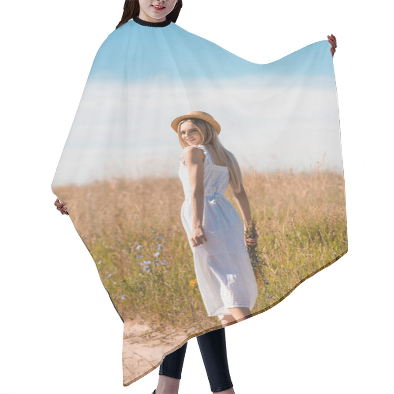 Personality  Young Blonde Woman In Straw Hat And White Dress Holding Wildflowers And Looking At Camera While Walking On Road In Field Hair Cutting Cape