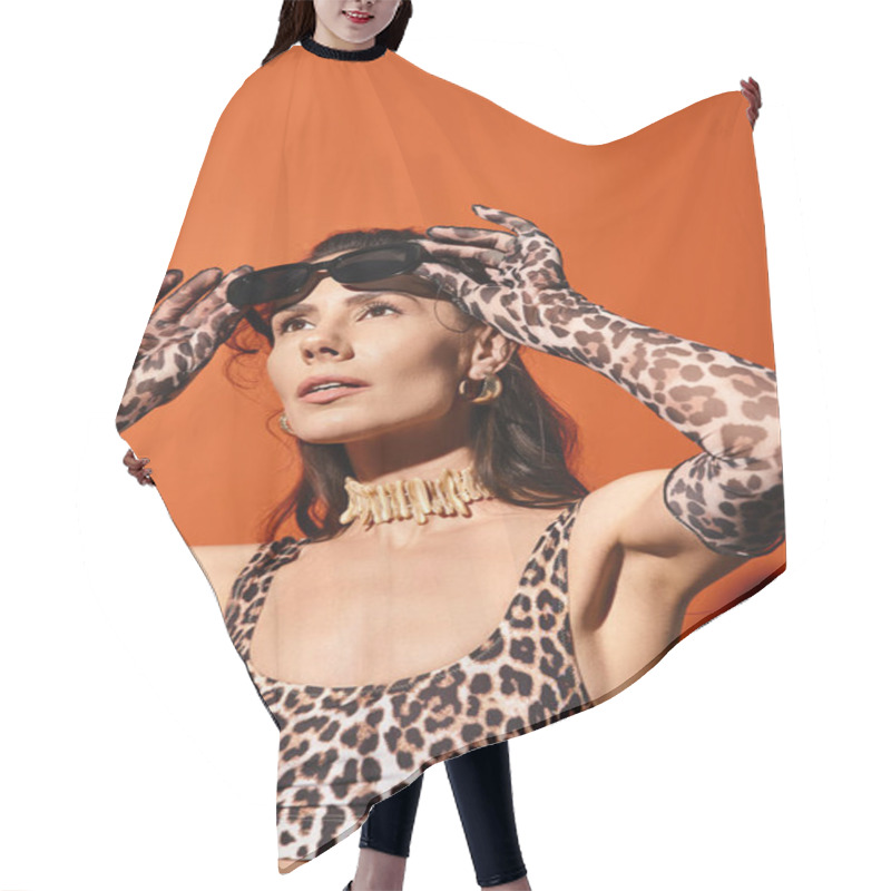 Personality  A Stylish Woman In A Leopard Print Top Holds Her Hands On Her Head In A Vibrant Orange Studio During A Summertime Fashion Shoot. Hair Cutting Cape