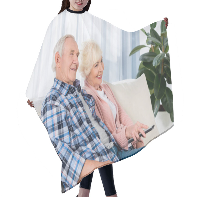 Personality  Happy Senior Couple With Remote Control Watching Tv On Couch Hair Cutting Cape