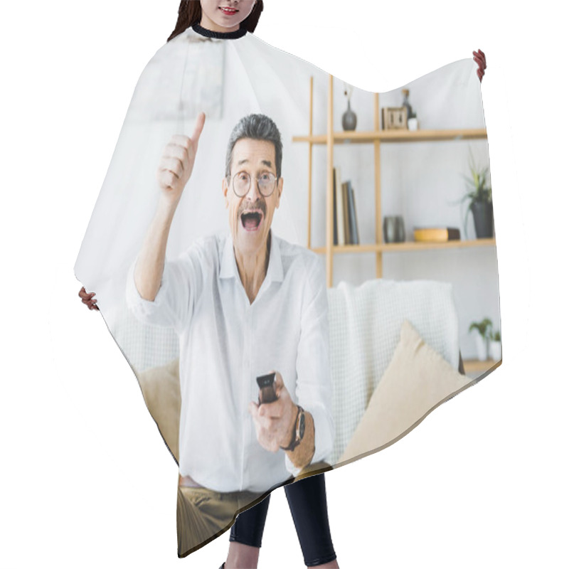 Personality  Happy Senior Man With Mustache Holding Remote Control And Showing Thumb Up At Home Hair Cutting Cape