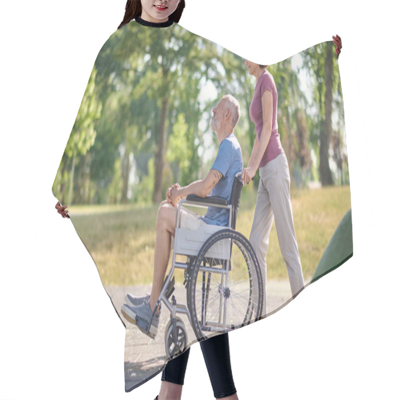 Personality  A Woman Carrying Her Husband In A Wheel Chair In A Park Hair Cutting Cape