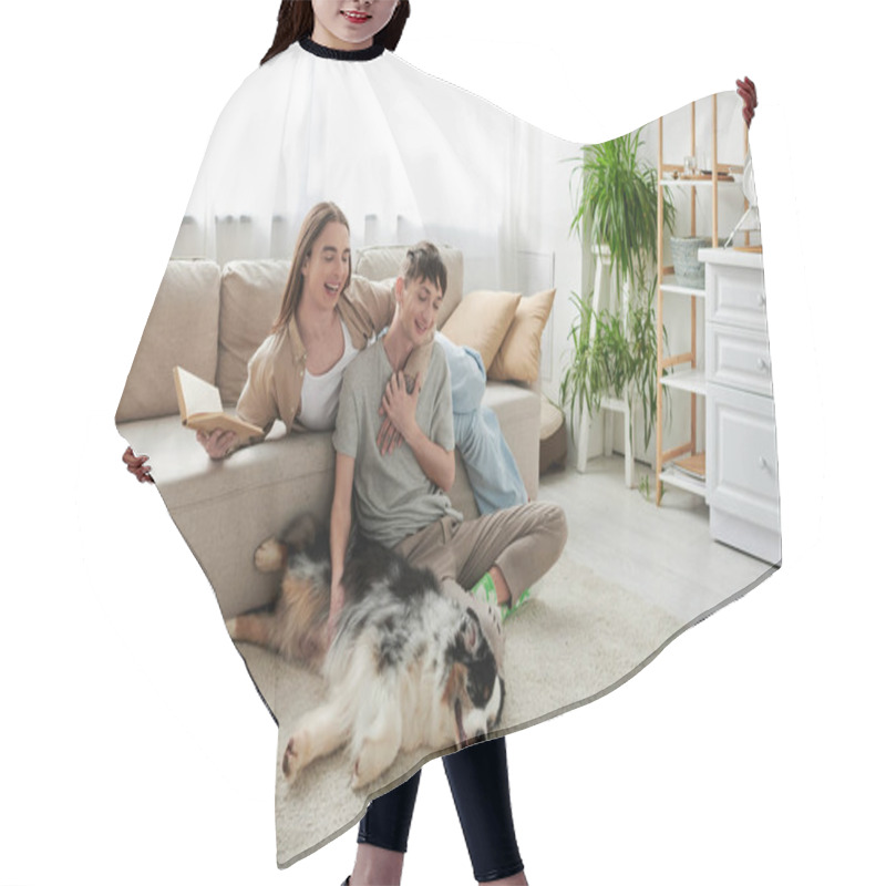 Personality  Cheerful Man Sitting On Carpet And Cuddling Australian Shepherd Dog And Touching Hand Of Gay Partner With Long Hair Holding Book In Modern Living Room  Hair Cutting Cape