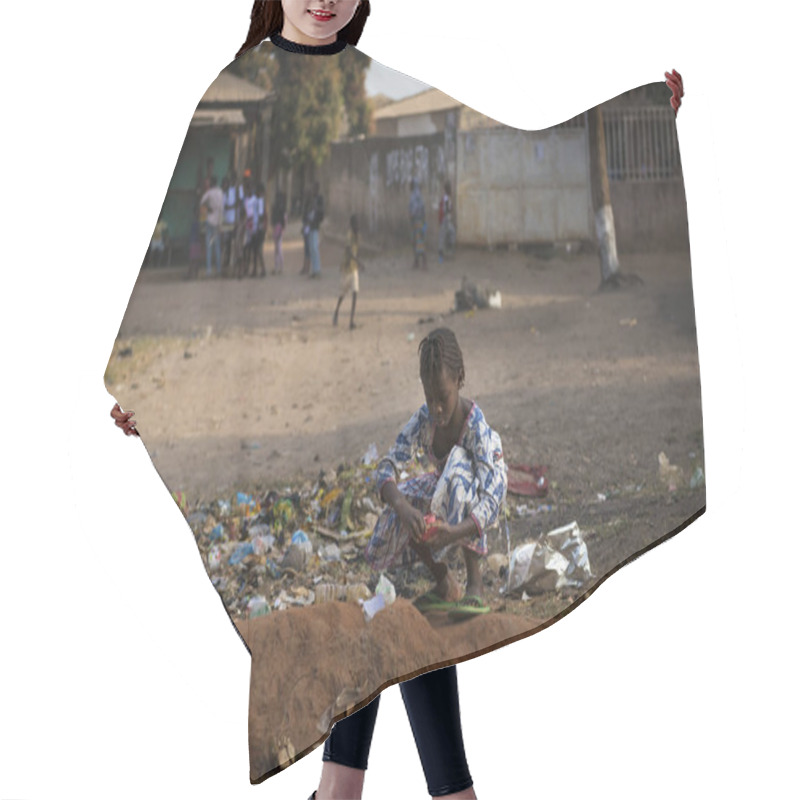 Personality  Bissau, Republic Of Guinea-Bissau - January 29, 2018: Young Girl Collecting Waste In A Street Of The Bissaque Neighborhood In The City Of Bissau, Guinea Bissau. Hair Cutting Cape