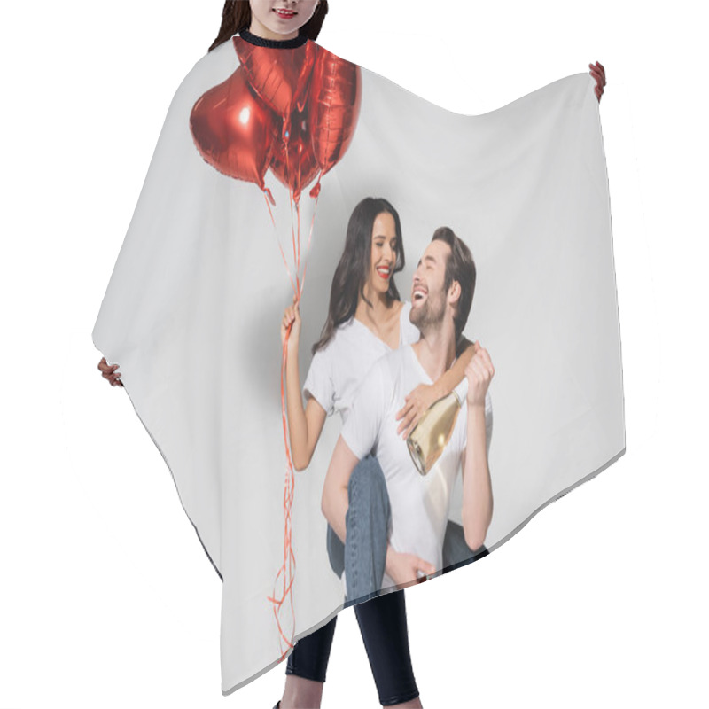 Personality  Cheerful Man With Champagne Bottle Piggybacking Woman With Red Heart-shaped Balloons On Grey Hair Cutting Cape