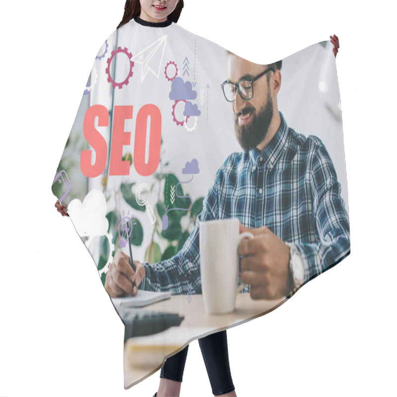 Personality  Successful Seo Manager With Cup Of Coffee And Computer Writing Notes At Workplace With SEO Icons Hair Cutting Cape