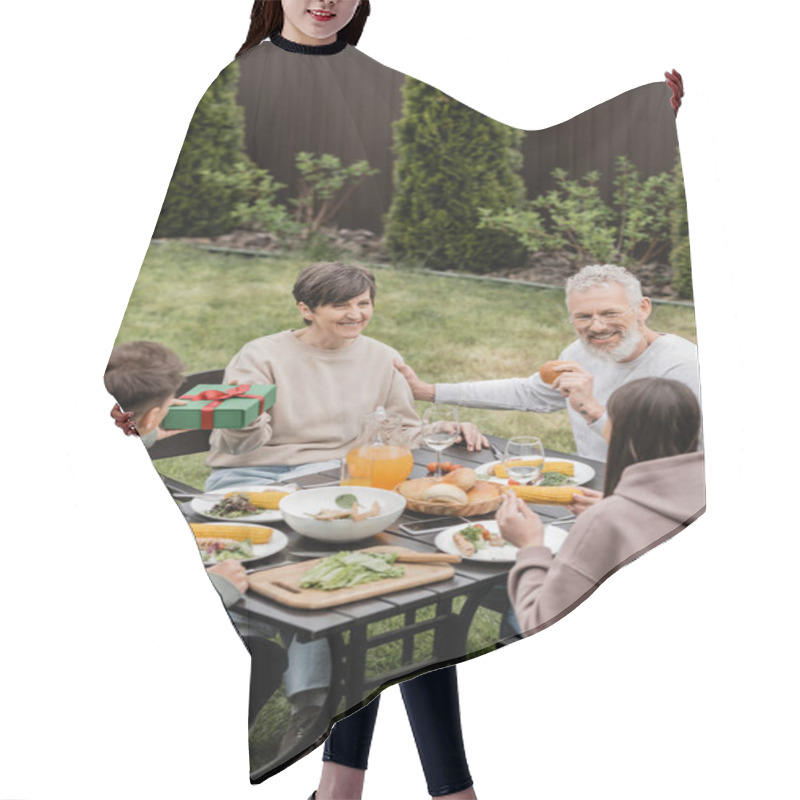 Personality  Young Son Giving Gift Box To Cheerful Middle Aged Mother Near Sister And Father While Celebrating Parents Day And Family Bbq Party At Backyard In June, Cherishing Family Bonds Concept Hair Cutting Cape