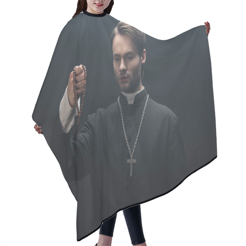 Personality  Young Tense Catholic Priest Looking At Wooden Rosary Beads Isolated On Black Hair Cutting Cape