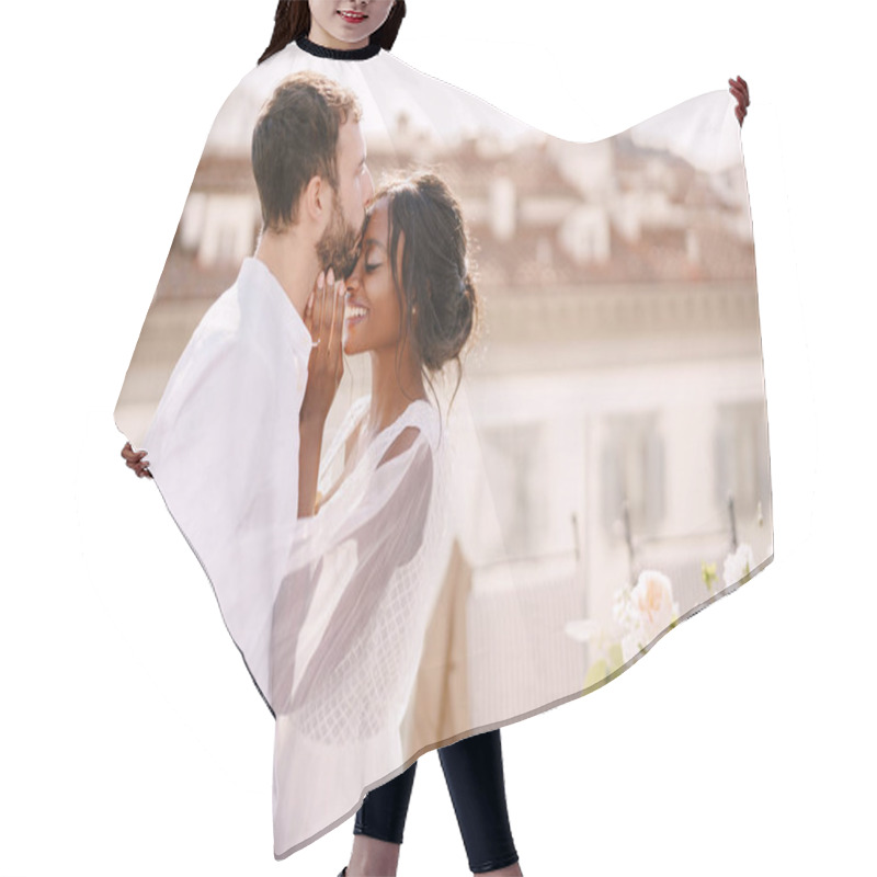 Personality  Destination Fine-art Wedding In Florence, Italy. Caucasian Groom And African-American Bride Cuddling On A Rooftop In Sunset Sunlight. Multiracial Wedding Couple Hair Cutting Cape